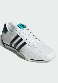 Biele kožené tenisky s čiernymi a tyrkysovými akcentmi, s dizajnom troch pruhov, zaoblenou špičkou a textúrovanou podrážkou pre lepšiu priľnavosť.