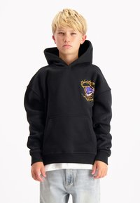 Zwarte capuchontrui met een zak aan de voorkant, oversized pasvorm en een kleurrijke afbeelding op de borst gestikt. Zachte, gestructureerde stof.