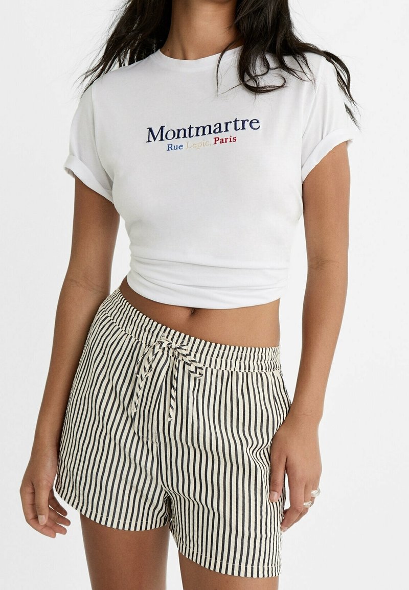 Biały krótki t-shirt z haftem "Montmartre". Spodenki w paski w kolorze kremowym i granatowym, z regulowanym paskiem na troczki i luźnym krojem.