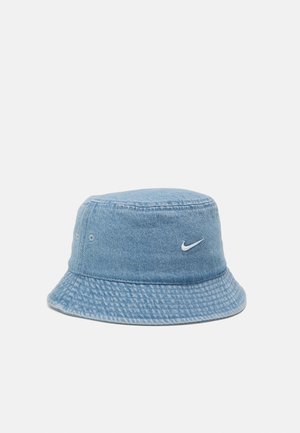 Lichtblauwe denim bucket hat met een klein wit Nike-swooshlogo aan de voorkant, weergegeven tegen een eenvoudige lichtgrijze achtergrond.