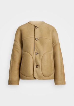 Giubbotto di pelle beige con una texture morbida, dotato di un colletto rotondo, due tasche frontali e una chiusura a bottone. Design semplice e strutturato.