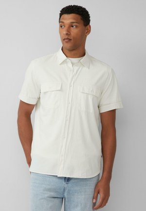 Korte mouwen witte shirt gemaakt van gestructureerde stof. Voorzien van een knoopsluiting aan de voorkant en twee zakken op de borst. Opgerolde mouwen en een relaxte pasvorm.