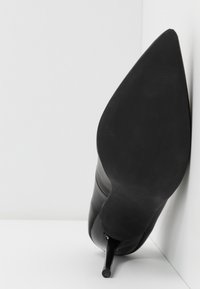 Schwarzer High-Heel-Schuh mit spitzer Zehenform und glattem Ledertextur. Verfügt über einen schlanken Stiletto-Absatz und minimalistisches Design.