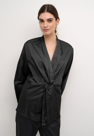 Camicia nera con bottoni realizzata in tessuto liscio, caratterizzata da un collo a V, design avvolgente e maniche lunghe con dettaglio a fiocco in vita.