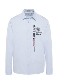 Himmelblaues Langarmhemd mit Button-Down-Kragen, das schwarze und rote Textgrafiken auf der linken Seite aufweist. Hergestellt aus einem strukturierten Stoff.