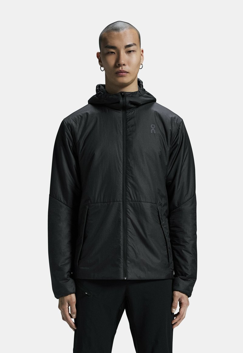 Veste légère noire avec fermeture éclair intégrale et capuche, dotée d'une texture lisse et d'un détail de logo sur la poitrine. Convient pour un port polyvalent.