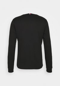 Long-sleeve black t-shirt with a round neckline, featuring a small colored accent at the back and ribbed cuffs. Smooth texture, casual design.