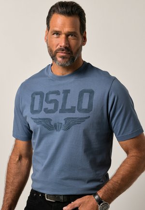 Blaue Baumwoll-T-Shirt mit kurzen Ärmeln, das das Wort "OSLO" und ein Flügelmotiv in dunklem Druck zeigt. Kombiniert mit schwarzen Hosen und einer Uhr.