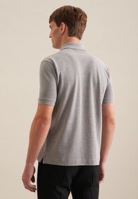 Polo grigio con maniche corte, colletto a coste e spacco laterale. Tessuto liscio e design aderente. Dettaglio di cucitura visibile all'orlo.