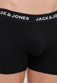 Schwarze Boxershorts mit schmalem Schnitt, ausgestattet mit einem bequemen elastischen Bund, der in weißer Schrift mit "JACK & JONES" markiert ist. Glatte Stoffoberfläche.