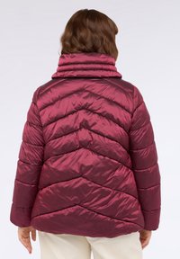 Bordeauxfarbene Puffjacke mit hohem Kragen, ausgestattet mit einem Chevron-Steppmuster und glänzendem Stoff. Weiches, leichtes und tailliertes Design.