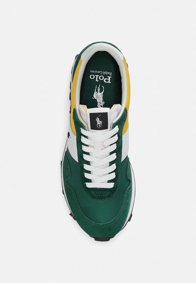 Πράσινο αθλητικό παπούτσι από δέρμα σουέντ και ύφασμα με λευκές λεπτομέρειες, κίτρινη διακόσμηση στα πλευρά, στρογγυλεμένη μύτη και λευκά κορδόνια. Φέρει λογότυπο στη γλώσσα του παπουτσιού.