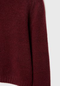 Burgundy knit sweater, soft texture, loose fit, ribbed hem, and cuffs. The fabric appears warm and slightly fuzzy, with even color distribution.