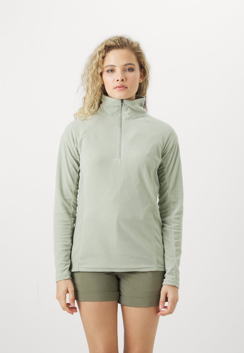 Hellgrüner Fleece-Pullover mit hohem Kragen und einem halben Reißverschluss an der Vorderseite. Hat lange Ärmel und eine weiche, strukturierte Oberfläche. Getragen mit olivfarbenen Shorts.