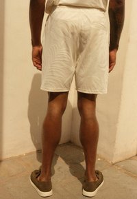 Shorts albe, texturate, cu un model de frunze de palmier, având o croială confortabilă și un talie elastică. Asortați cu pantofi slip-on de culoare verde măsliniu.
