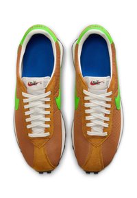 Smeđe i zelene atletske cipele s teksturiranim gornjim dijelom od tkanine, bijelim vezicama i plavim uloškom. Imaju zeleni Nike logotip sa strane.