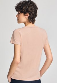 Ljusrosa t-shirt med kort ärm och rund halsringning, i figurnära passform, tillverkad av mjuk bomull med en slät textur.