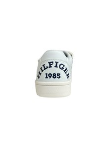 Sneaker in pelle bianca con suola testurizzata, logo posteriore "HILFIGER" e "1985" in blu navy, dal design minimal e senza ulteriori accenti.