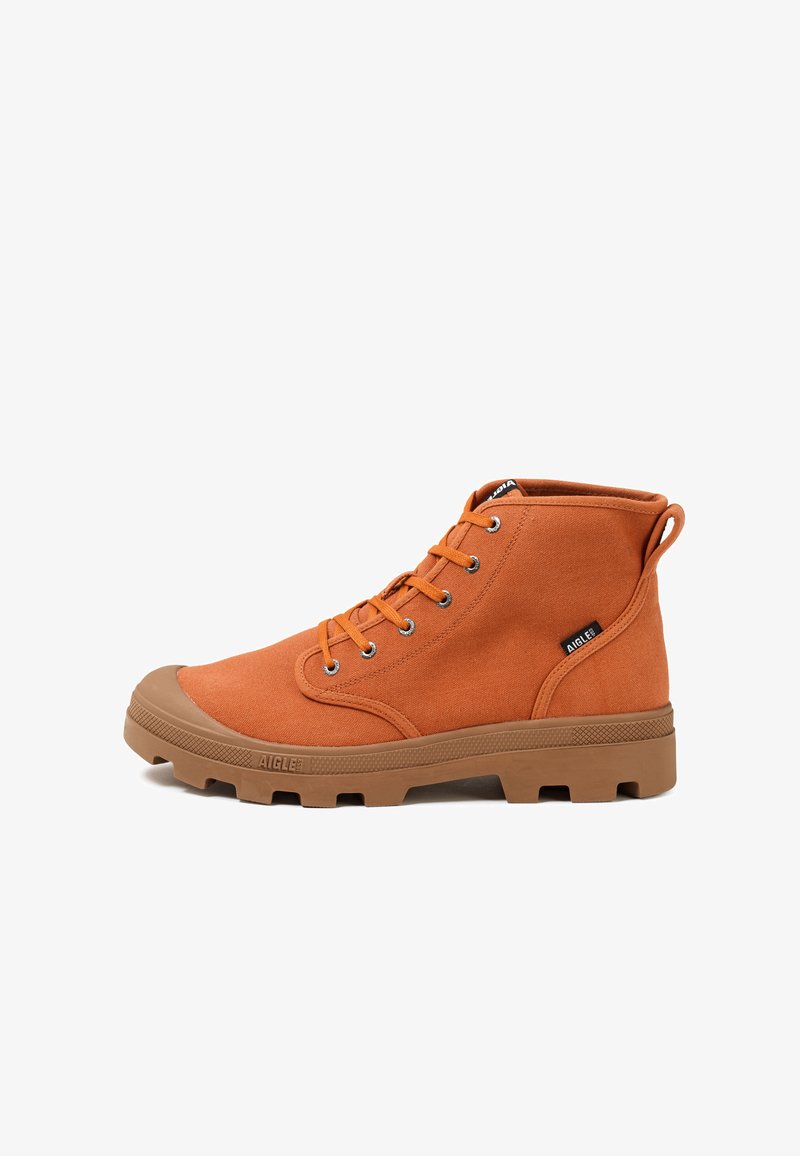 Botte montante en toile couleur rouille-orange avec semelle en caoutchouc marron, bout rond, fermeture à lacets à l'avant et languette de traction à l'arrière.