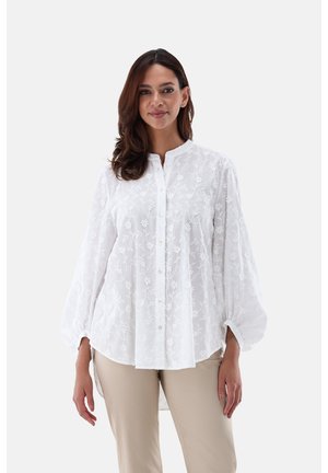 Weiße bestickte Bluse mit Knopfverschluss, Mandarin-Kragen und Ballonärmeln, die mit floralen Mustern und einem leichten Stoff versehen ist.
