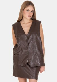 Gilet in finta pelle marrone con scollo a V, bottoni a scatto frontali, grandi tasche e design senza maniche. Texture liscia con finitura lucida.