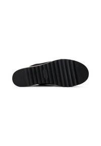 Suela de zapato negra con profundas ranuras horizontales y un logotipo rectangular grabado en el centro, aislada sobre un fondo blanco.