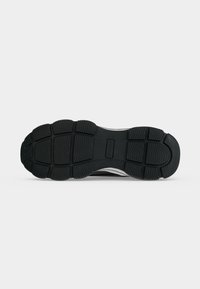 Μαύρη ελαστική σόλα sneaker με τμηματικά σχέδια πέλματος και υφασμένο σχεδιασμό λαβής για πρόσφυση και ευκαμψία.