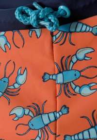 Un maillot de bain en tissu orange vif avec un motif de homard bleu. Comprend un cordon bleu et une taille bleu foncé.