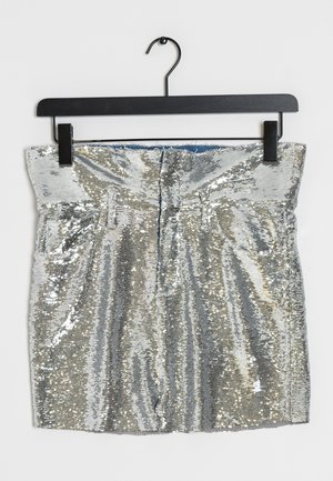 Mini-jupe argentée à sequins avec taille haute et passants pour ceinture suspendue sur un cintre noir sur fond blanc.