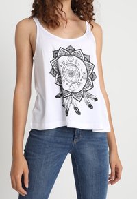 Débardeur blanc avec un motif graphique noir composé de motifs mandala et de plumes. Confectionné dans un tissu doux, il présente une coupe décontractée et des larges bretelles.