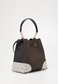 Borsa a mano marrone e nera con motivo, manico nero, accessori in oro e dettagli color crema alla base che mostrano un motivo a monogramma.