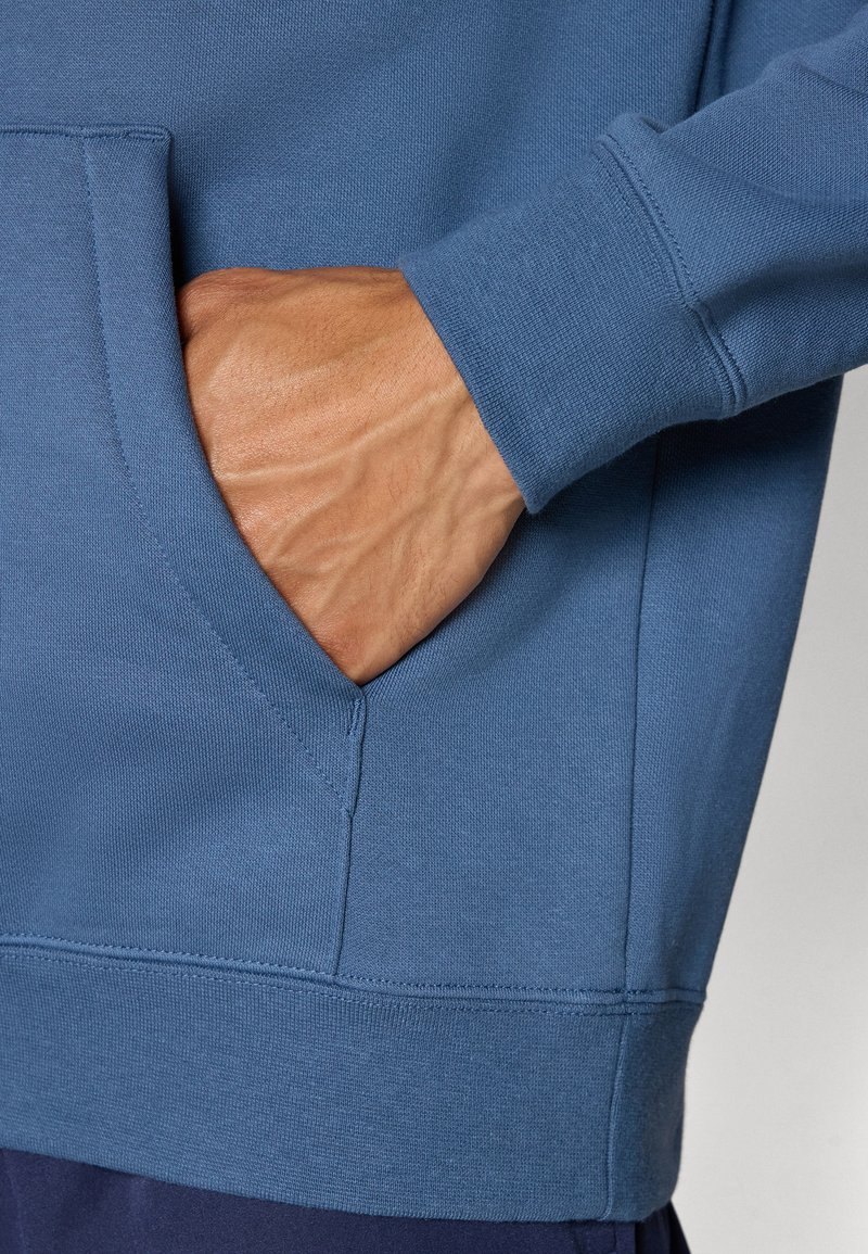 Blauwe sweatshirt met een voorzak, ribbels aan de mouwen en onderkant. De stof heeft een gladde textuur en een losse pasvorm.