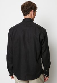 Zwarte lange mouwen shirt van gestructureerd linnen, met een standaard kraag, knoopmanchetten en een ontspannen pasvorm, met een gebogen zoom.