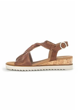 Brown leather sandal with crossed straps, cork wedge heel, and white rubber sole. Features an adjustable buckle for fit.