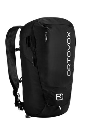 Black Ortovox Trace 20 backpack with padded shoulder strap, front zipper compartment, and white vertical logo on the main body.