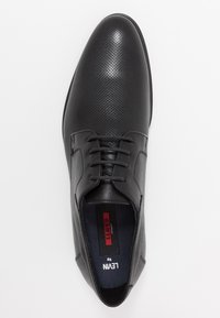 Chaussure habillée en cuir noir avec un design perforé, bout rond, lacets classiques et accents texturés sur la tige. L'intérieur est doté d'une semelle intérieure de marque.
