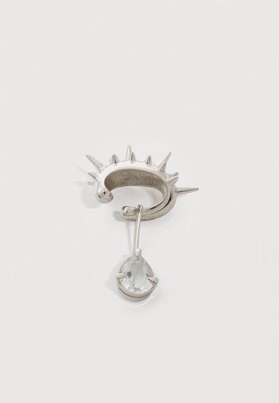 Srebrna uhan obroč s številnimi ostrimi konicami in visečim prozornim dragim kamnom v obliki solzice na tanki zatiču.