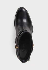 Bota de couro preta até o tornozelo com bico pontiagudo, fecho de zíper interior e detalhes em metal dourado. Textura suave e costura ao longo da borda.