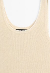 Canottiera beige a costine con scollatura rotonda. Il tessuto è texturizzato e morbido, con un piccolo etichetta del marchio al centro della parte posteriore.