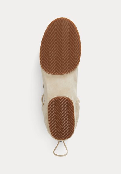 Σόλα παπουτσιού από μπεζ σουέντ με καφέ ελαστικό πέλμα σε σχέδιο ψαροκόκκαλο, με τράβηγμα στη φτέρνα σε λευκό φόντο.