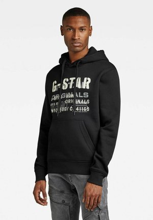 Schwarzer Kapuzenpullover mit weißen Grafiken, darunter "G-STAR" und Textdetails. Mit einer Kängurutasche und gerippten Bündchen. Weicher Stoff.