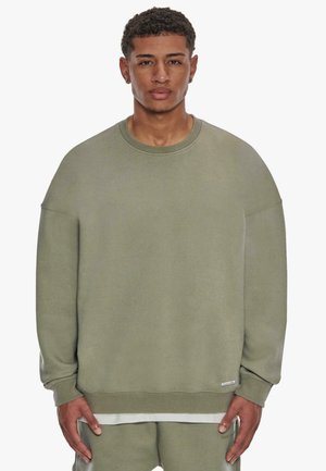 Olive green, oversized sweatshirt with a round neckline and drop shoulder design. Soft cotton material, ribbed cuffs, and hem.