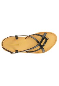 Sort lædersandal med fletdetalje, tan fodsenge og flad sål. Har krydsede remme og en sidelås til justering af pasformen.