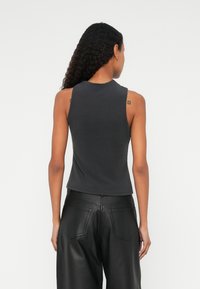 Silm-fit, ilma varrukat must topp ümmarguse kaelusega, pehme tekstuuriga ja lühendatud disainiga, koos kõrge vöökohaga mustade kunstnahkpükstega.