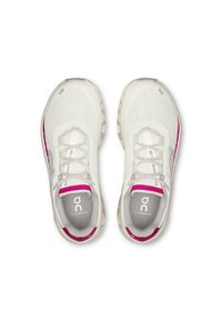 Un paio di scarpe da corsa On Cloudmonster bianche e rosa viste dall'alto, che mostrano i lacci e il logo sulla linguetta e sulla soletta.