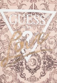 Tissu rose orné de motifs floraux, avec le logo "GUESS" en blanc et le mot "Love" en doré agrémenté de strass.