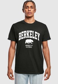 Černé bavlněné tričko s nápisem "BERKELEY" v tučných bílých písmenech, grafikou medvěda a nápisem "UNIVERSITY OF CALIFORNIA" níže v menším písmu.