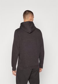Sweat-shirt à capuche gris foncé, en mélange de coton doux. Présente une coupe décontractée, des poignets côtelés et une finition légèrement texturée.