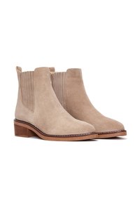 Stivaletti beige in suede con pannelli elastici laterali, punta rotonda e basso tacco impilato, caratterizzati da cuciture a contrasto lungo la suola.