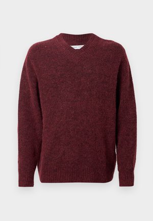 Suéter de lana burdeos con escote en V, mangas largas y puños y dobladillo acanalados. Textura suave y corte relajado, ideal para superponer.